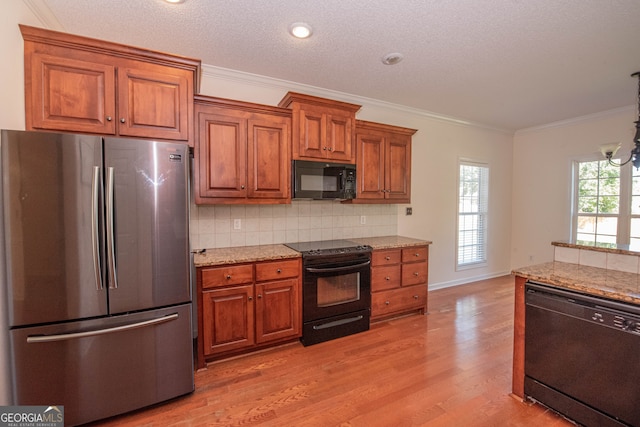 kitchen with black appliances, light stone countertops, tasteful backsplash, light hardwood / wood-style floors, and crown molding