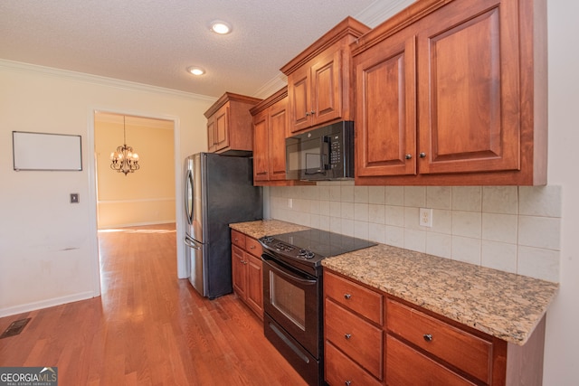 kitchen with ornamental molding, a textured ceiling, black appliances, light wood-type flooring, and decorative backsplash