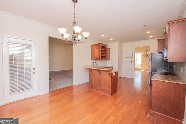 kitchen with pendant lighting, ornamental molding, sink, light wood-type flooring, and a kitchen bar