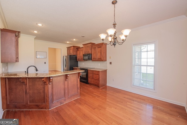 kitchen with light wood-type flooring, black appliances, kitchen peninsula, ornamental molding, and decorative light fixtures