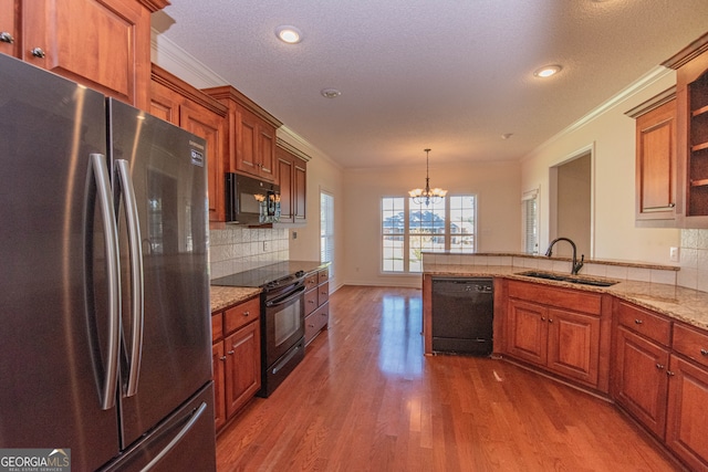 kitchen with black appliances, hardwood / wood-style floors, sink, hanging light fixtures, and a textured ceiling