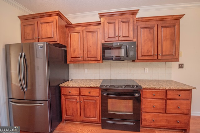 kitchen with light wood-type flooring, black appliances, decorative backsplash, and light stone countertops