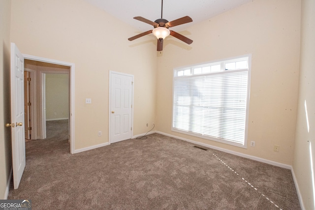 unfurnished bedroom featuring carpet floors, a towering ceiling, and ceiling fan