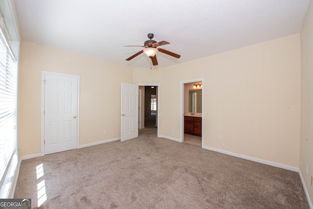 unfurnished bedroom featuring ceiling fan, light colored carpet, and connected bathroom