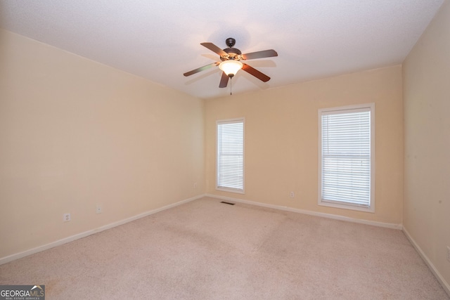 carpeted empty room featuring a wealth of natural light and ceiling fan