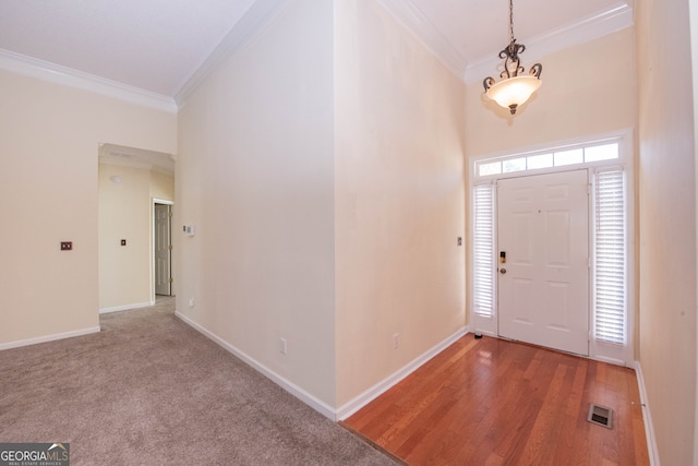 foyer entrance with crown molding and wood-type flooring