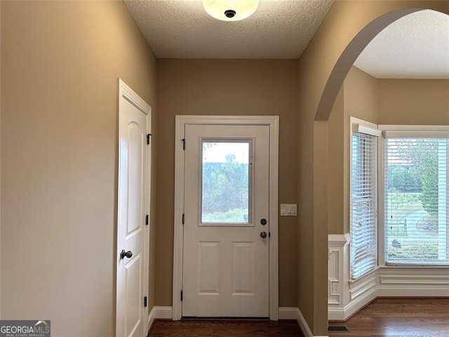 doorway to outside featuring a textured ceiling and dark wood-type flooring