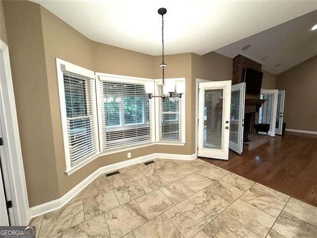 unfurnished dining area featuring wood-type flooring, a fireplace, and an inviting chandelier