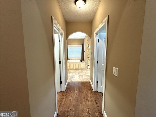 corridor with wood-type flooring and a textured ceiling