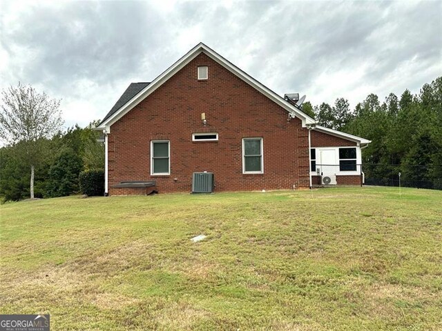 view of side of home with central air condition unit and a yard