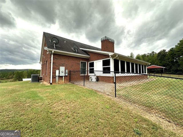 back of property featuring a yard and central AC