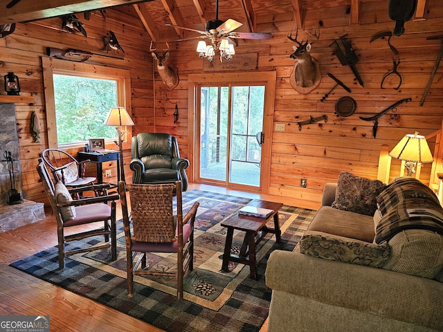 living room with hardwood / wood-style flooring, a healthy amount of sunlight, wooden walls, and vaulted ceiling with beams