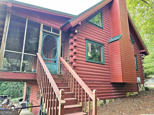 view of home's exterior featuring a sunroom, stairway, and log siding