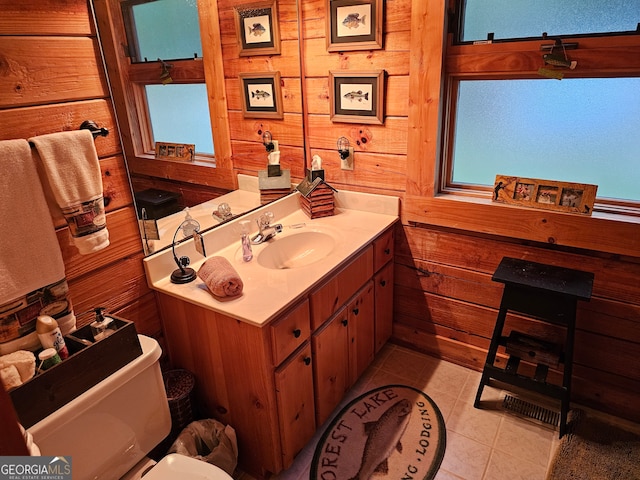 bathroom with toilet, vanity, wooden walls, and tile patterned flooring