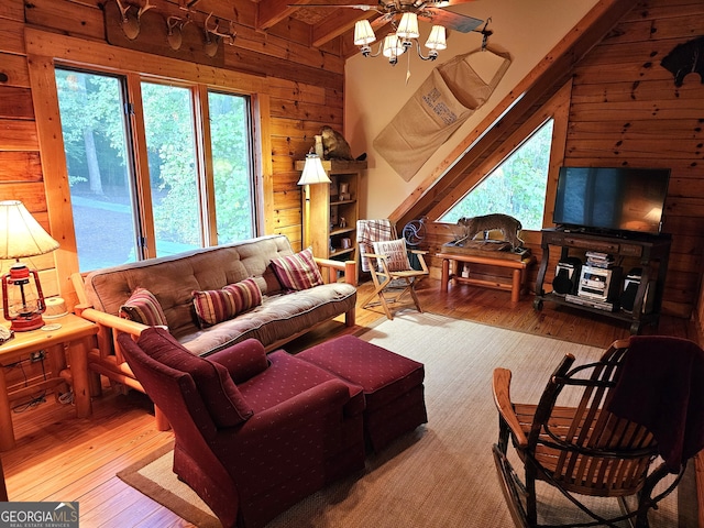 living room with hardwood / wood-style floors, ceiling fan, wood walls, and lofted ceiling with beams