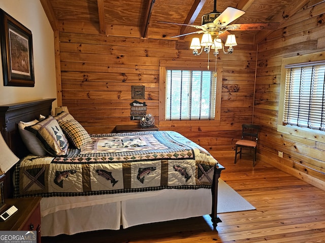 bedroom with lofted ceiling with beams, wooden walls, ceiling fan, and light hardwood / wood-style flooring