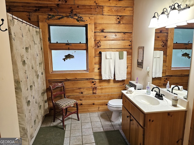 bathroom featuring wood walls, vanity, tile patterned floors, and toilet