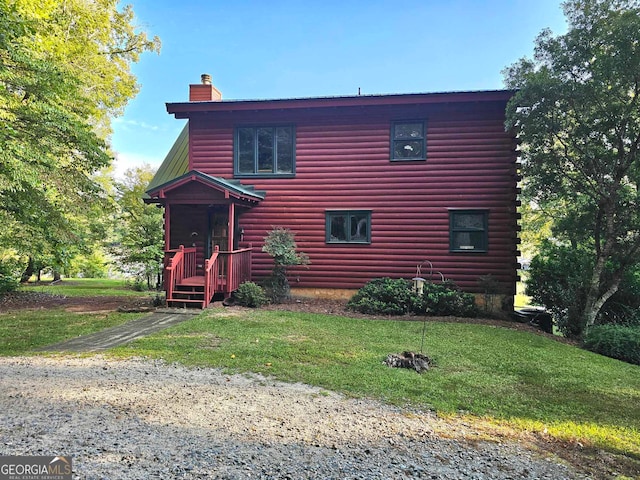 cabin with a chimney and a front lawn