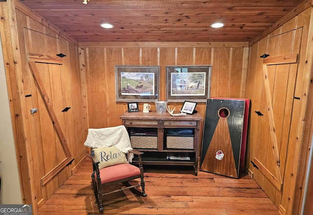 sitting room with light hardwood / wood-style floors, wooden walls, and wood ceiling