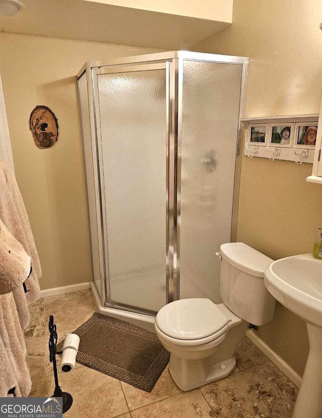 bathroom featuring tile patterned floors, toilet, sink, and a shower with door