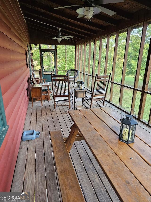 unfurnished sunroom featuring wooden ceiling, beamed ceiling, plenty of natural light, and ceiling fan