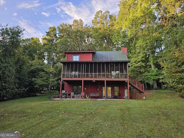 rear view of property with a lawn, a sunroom, and a patio