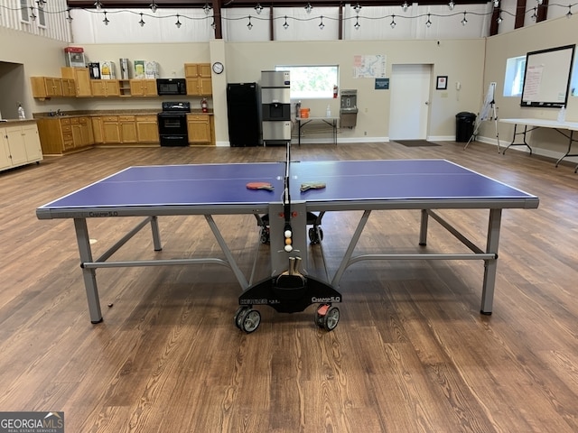 game room with hardwood / wood-style floors and a high ceiling