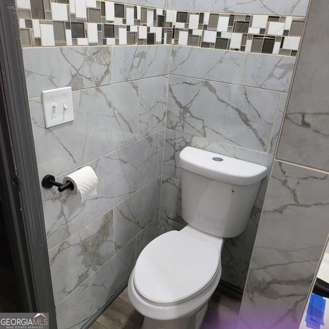 bathroom with tile walls and toilet