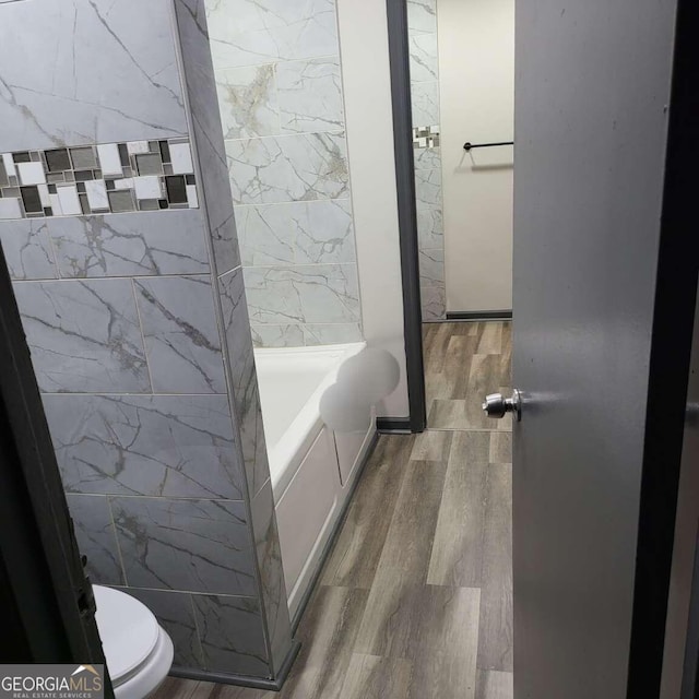 bathroom with a bathtub, tile walls, toilet, and hardwood / wood-style flooring