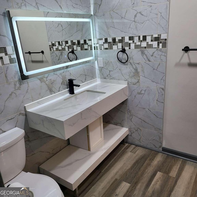 bathroom featuring wood-type flooring, tile walls, and toilet