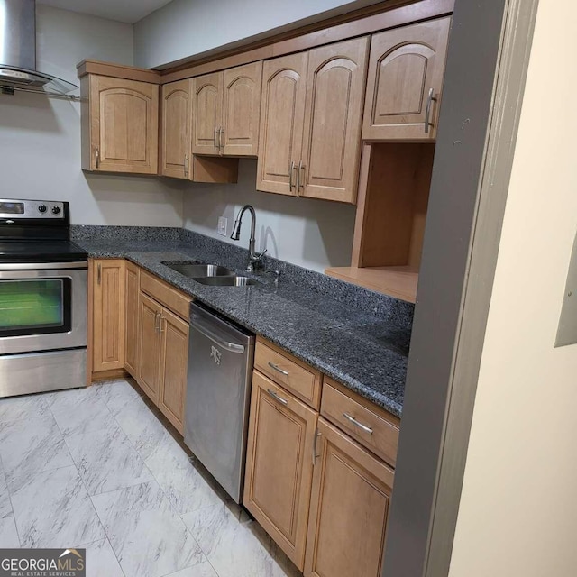 kitchen with appliances with stainless steel finishes, wall chimney exhaust hood, dark stone countertops, and sink