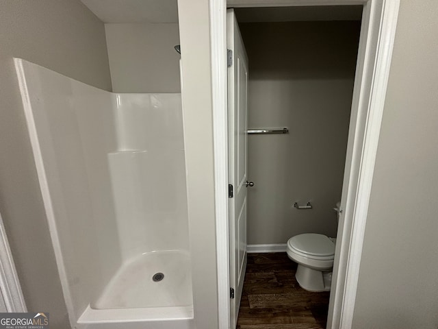 bathroom with hardwood / wood-style flooring, walk in shower, and toilet