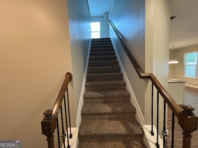 stairway with carpet floors and a notable chandelier