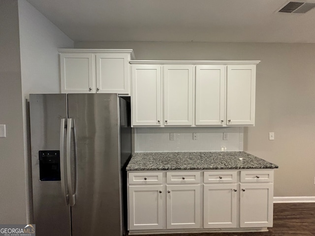 kitchen with stainless steel refrigerator with ice dispenser, dark stone countertops, dark hardwood / wood-style flooring, and white cabinets