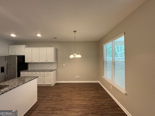 kitchen with pendant lighting, dark stone counters, dark wood-type flooring, white cabinets, and stainless steel fridge