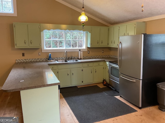 kitchen featuring kitchen peninsula, vaulted ceiling, sink, stainless steel refrigerator, and hanging light fixtures