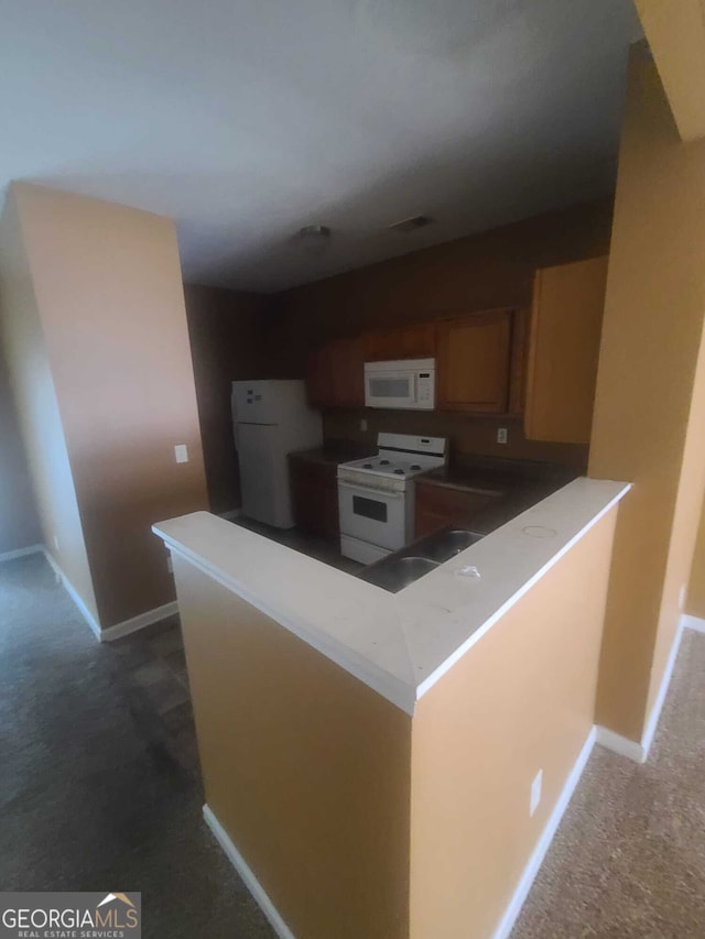 kitchen with dark carpet, white appliances, and kitchen peninsula