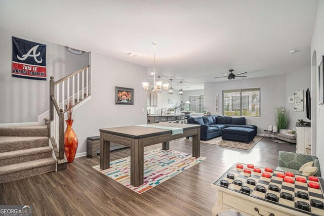 game room with ceiling fan with notable chandelier and dark hardwood / wood-style flooring