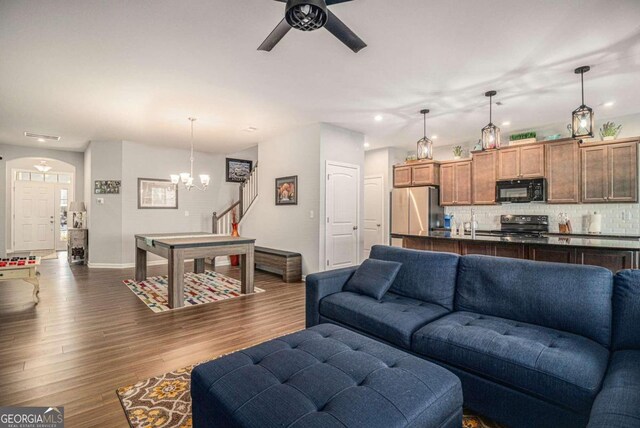 living room with ceiling fan with notable chandelier and dark wood-type flooring