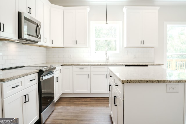 kitchen with tasteful backsplash, white cabinetry, stainless steel appliances, and light hardwood / wood-style floors