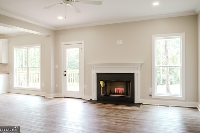 unfurnished living room with plenty of natural light, ceiling fan, light wood-type flooring, and ornamental molding