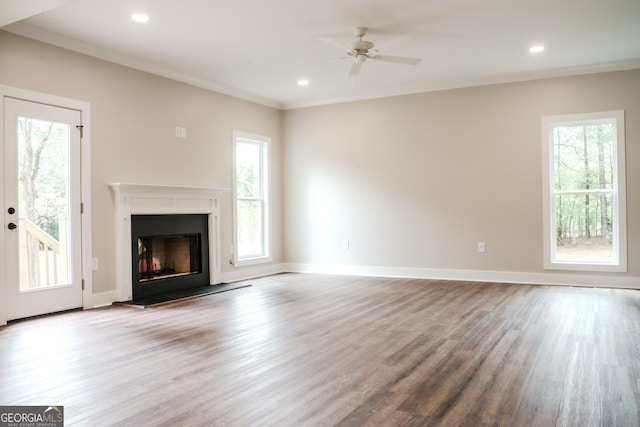 unfurnished living room with plenty of natural light, ceiling fan, ornamental molding, and light hardwood / wood-style flooring