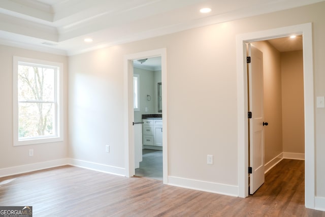 unfurnished bedroom featuring wood-type flooring, crown molding, and connected bathroom