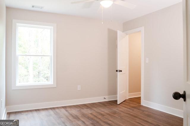 unfurnished room featuring a wealth of natural light, ceiling fan, and dark hardwood / wood-style floors