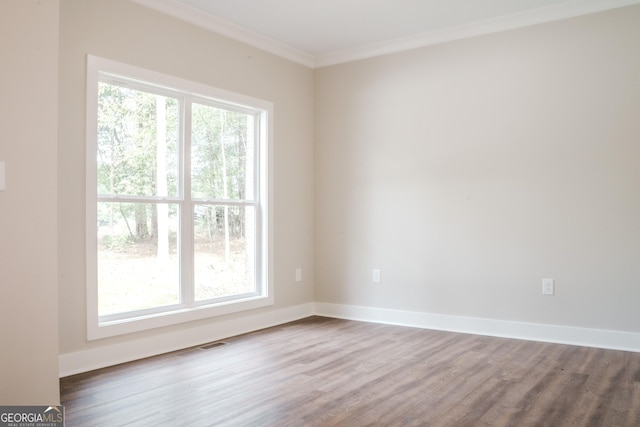 empty room with hardwood / wood-style floors, a healthy amount of sunlight, and ornamental molding