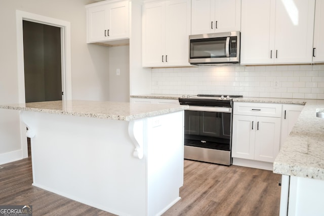 kitchen with white cabinets, stainless steel appliances, light hardwood / wood-style flooring, and a kitchen island