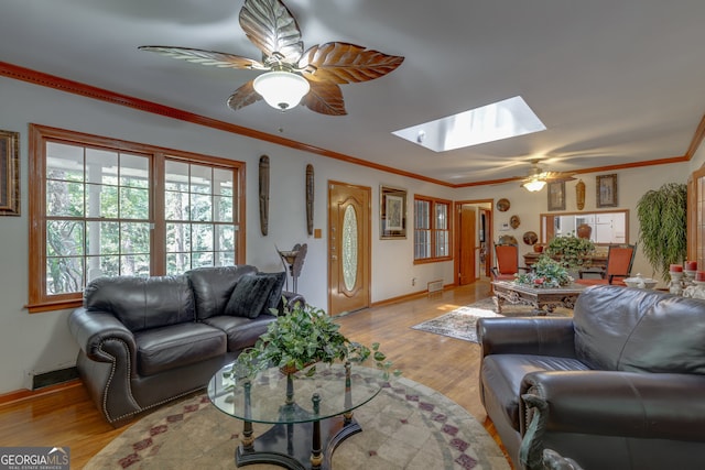 living room featuring ornamental molding, ceiling fan, light hardwood / wood-style flooring, and a skylight