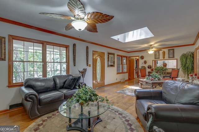 living room featuring ornamental molding, light hardwood / wood-style floors, a skylight, and ceiling fan