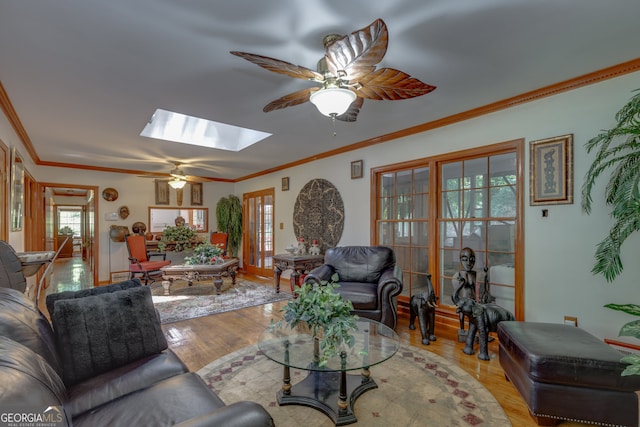 living room featuring light hardwood / wood-style floors, a skylight, ceiling fan, and crown molding