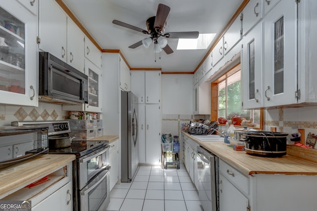 kitchen featuring appliances with stainless steel finishes, backsplash, light tile patterned flooring, and white cabinets